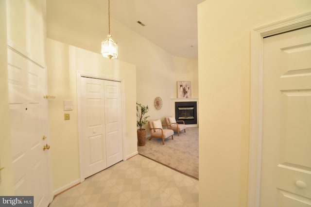 foyer entrance with light carpet, a glass covered fireplace, baseboards, and visible vents