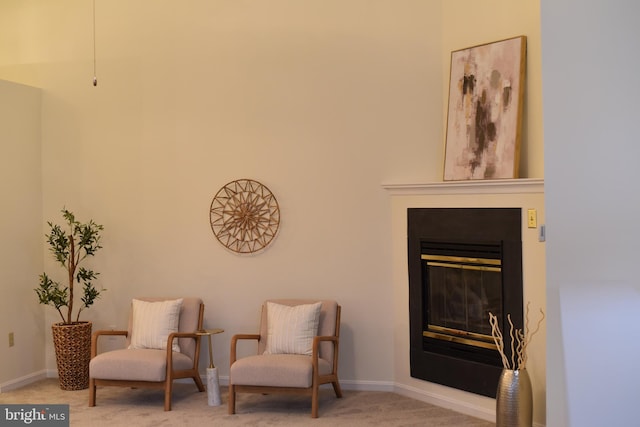 living area with a glass covered fireplace, carpet flooring, and baseboards