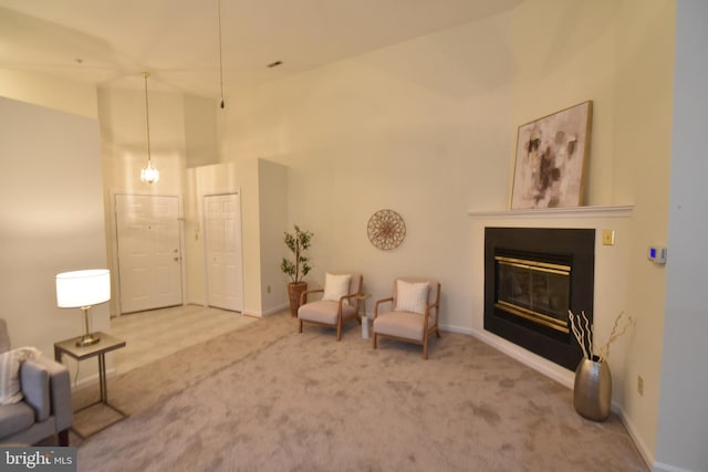 sitting room featuring carpet flooring, a high ceiling, baseboards, and a glass covered fireplace