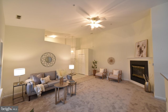 living area with baseboards, visible vents, ceiling fan, a glass covered fireplace, and carpet flooring