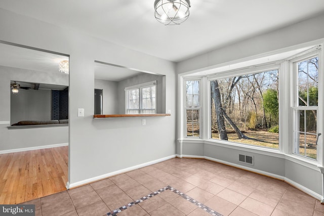 unfurnished dining area with tile patterned floors, visible vents, baseboards, and ceiling fan