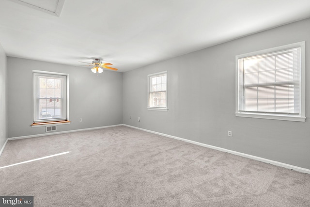 carpeted spare room with a ceiling fan, visible vents, and baseboards