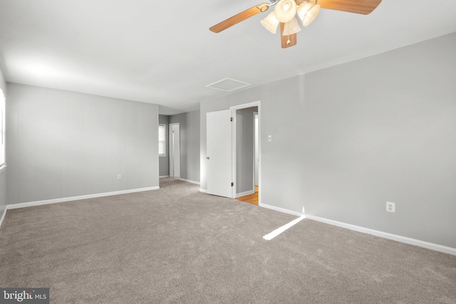 unfurnished room with baseboards, carpet, attic access, and a ceiling fan