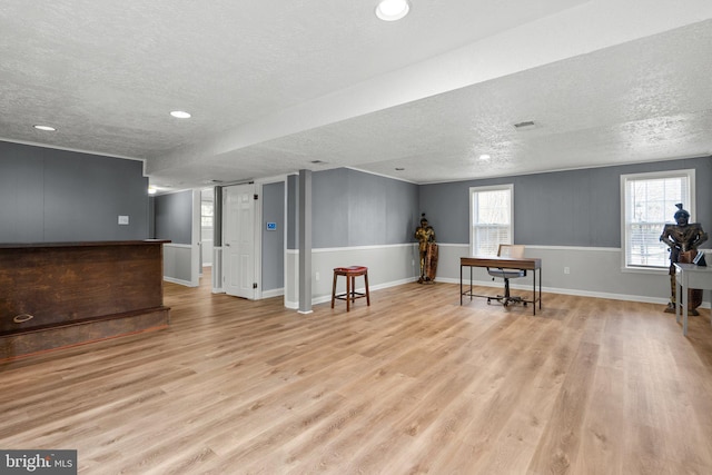 interior space with baseboards, a textured ceiling, and light wood finished floors