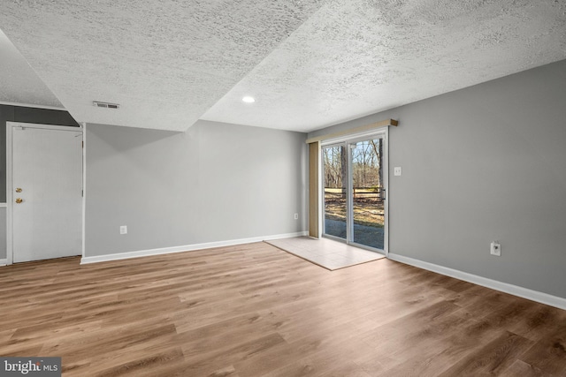 unfurnished room featuring visible vents, baseboards, and wood finished floors