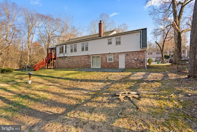 rear view of property featuring stairs, a yard, brick siding, and a chimney