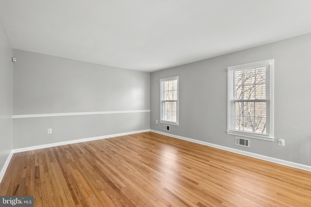 empty room featuring light wood-type flooring, baseboards, and visible vents