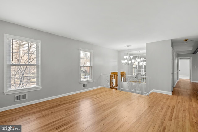 interior space featuring visible vents, baseboards, an inviting chandelier, and wood finished floors