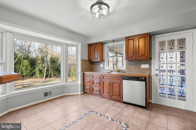 kitchen with visible vents, stainless steel dishwasher, light tile patterned flooring, and brown cabinetry