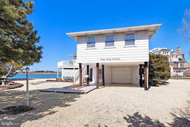 raised beach house with stairs, a carport, an attached garage, and driveway