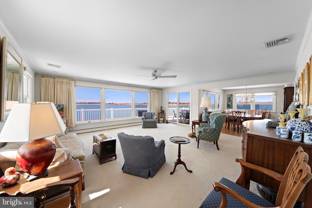 living room featuring visible vents, a baseboard heating unit, carpet, a wealth of natural light, and ceiling fan with notable chandelier