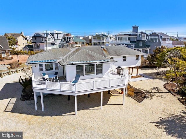 rear view of property with a wooden deck, a residential view, and roof with shingles