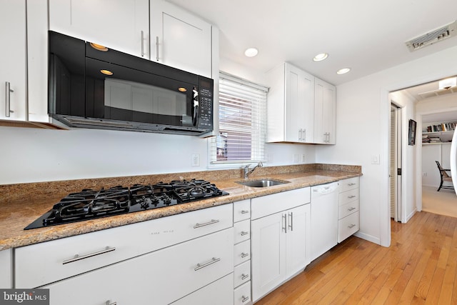 kitchen with visible vents, a sink, black appliances, light wood-style floors, and white cabinetry