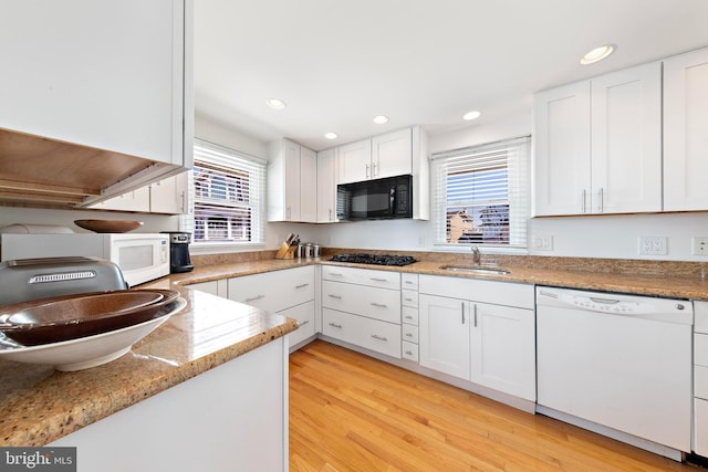 kitchen with black appliances, white cabinets, a wealth of natural light, and a sink