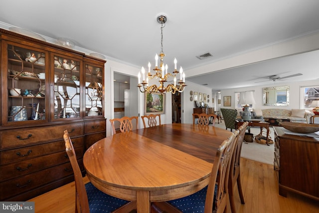 dining room featuring ornamental molding, ceiling fan with notable chandelier, visible vents, and light wood-type flooring