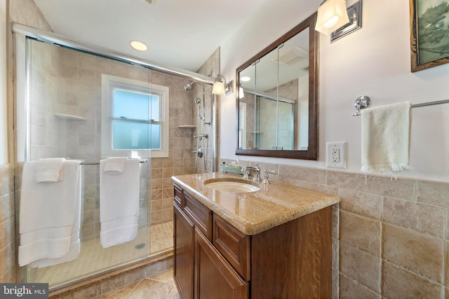 bathroom with vanity, tile walls, and a shower stall