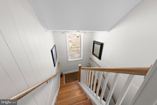 stairway featuring wood finished floors and ornamental molding