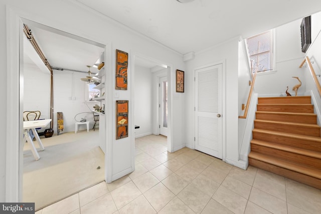 interior space featuring light tile patterned flooring, crown molding, and stairs