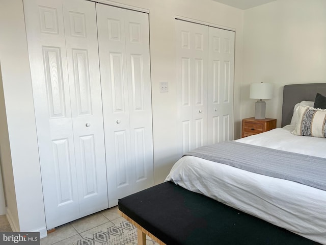 bedroom with light tile patterned floors and multiple closets