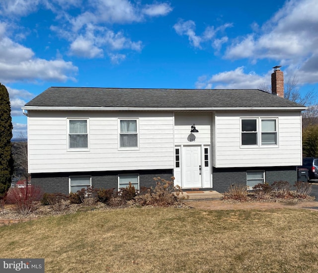 split foyer home featuring a chimney and a front lawn