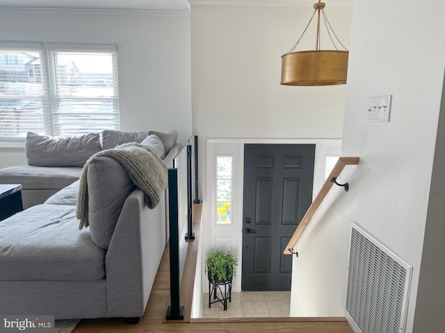 entrance foyer with crown molding, wood finished floors, and visible vents