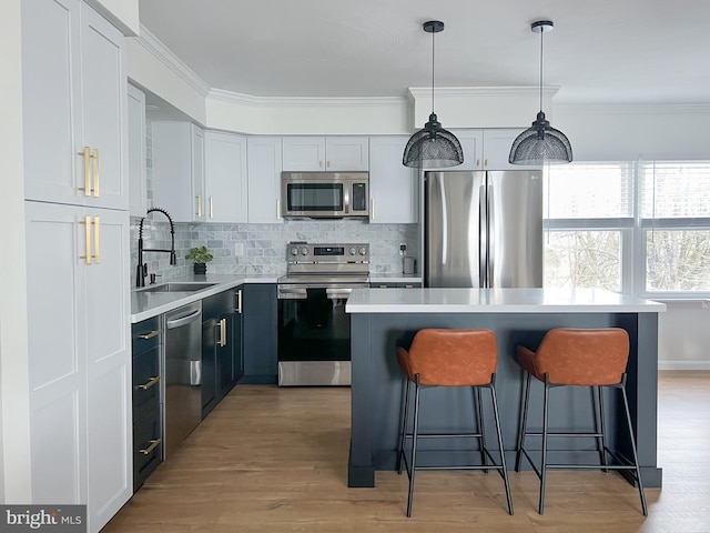 kitchen featuring a breakfast bar, ornamental molding, appliances with stainless steel finishes, and a sink