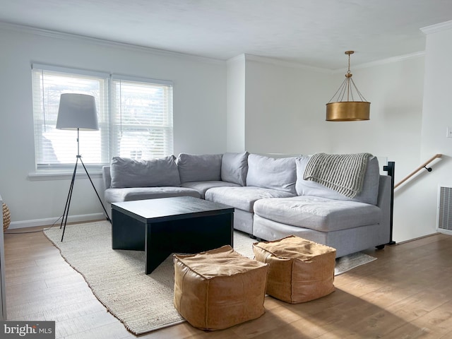 living area featuring crown molding, wood finished floors, baseboards, and visible vents