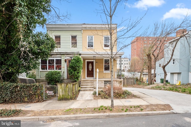 townhome / multi-family property with a fenced front yard, covered porch, and a gate