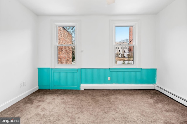 carpeted spare room featuring a wainscoted wall, baseboards, baseboard heating, and a baseboard radiator