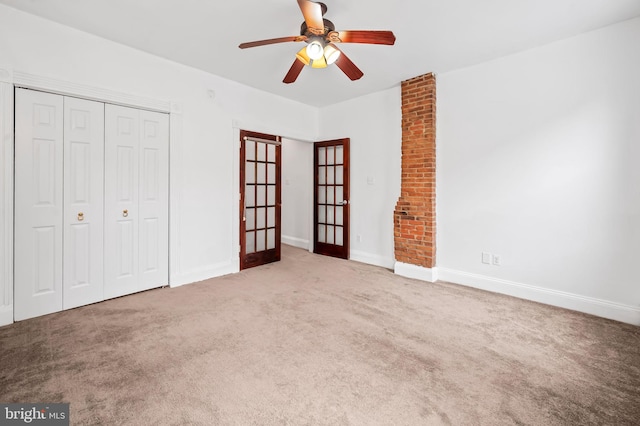 unfurnished bedroom featuring a closet, carpet floors, french doors, baseboards, and ceiling fan