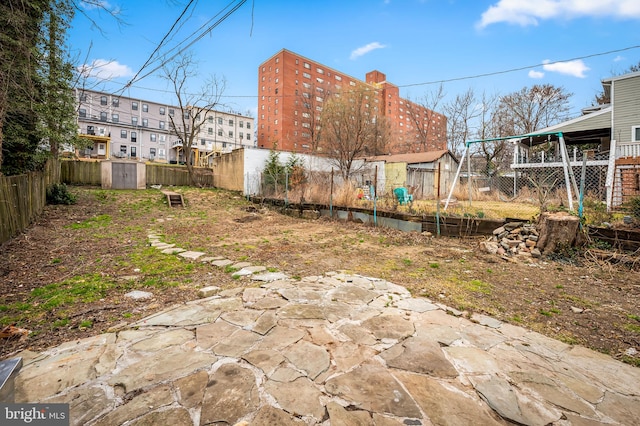 view of yard featuring a storage unit, a patio, an outdoor structure, and a fenced backyard