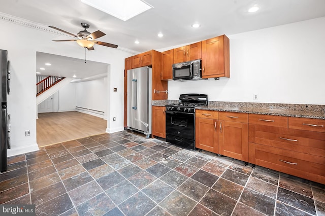 kitchen featuring high quality fridge, black gas range oven, a skylight, baseboard heating, and ceiling fan