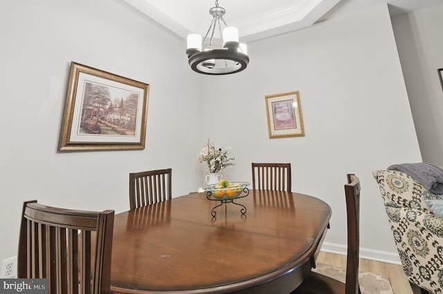 dining area featuring baseboards, a tray ceiling, wood finished floors, and a notable chandelier