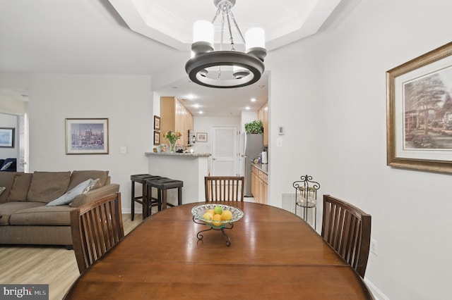 dining room featuring baseboards, a chandelier, wood finished floors, and a raised ceiling