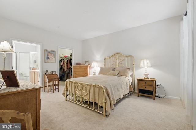 bedroom with baseboards, a closet, a spacious closet, ensuite bathroom, and light carpet