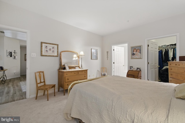 carpeted bedroom with baseboards and a walk in closet