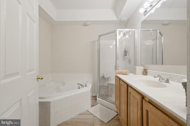 bathroom featuring vanity, a stall shower, a garden tub, and wood finished floors