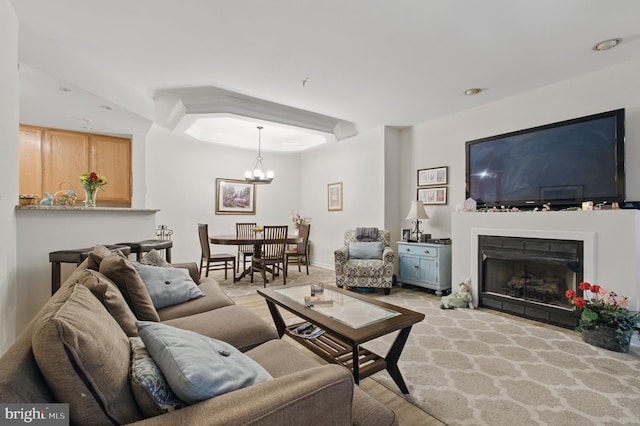 living area featuring light wood-style floors, a notable chandelier, and a fireplace
