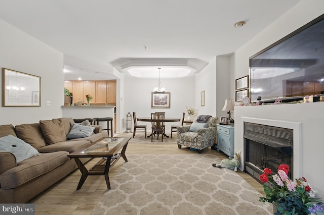 living room with a fireplace, an inviting chandelier, and light wood-style floors