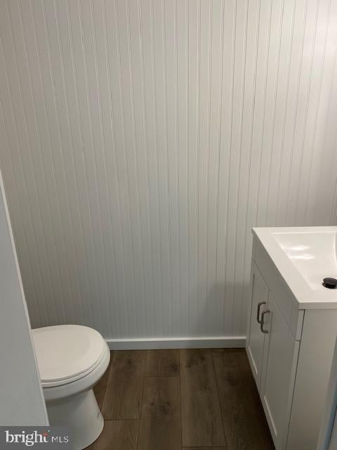 bathroom featuring toilet, vanity, baseboards, and wood finished floors