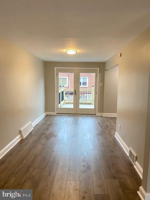 spare room with dark wood-style floors, visible vents, french doors, and baseboards