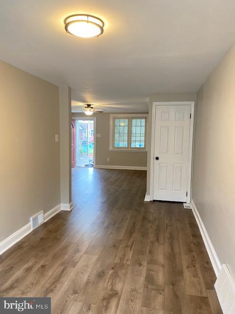 unfurnished room with visible vents, baseboards, dark wood-type flooring, and ceiling fan