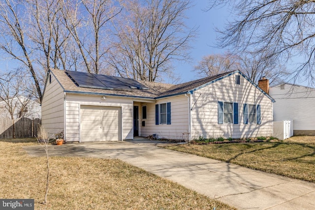 ranch-style house with fence, a front yard, roof mounted solar panels, driveway, and an attached garage