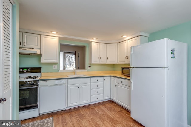 kitchen featuring a sink, under cabinet range hood, white appliances, light wood-style floors, and light countertops