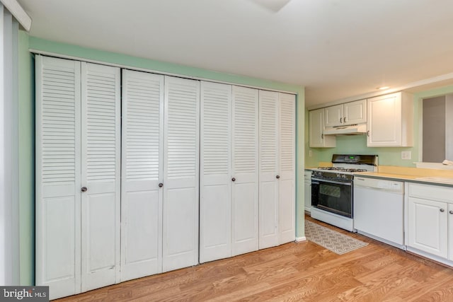 kitchen with under cabinet range hood, white appliances, light wood-style floors, white cabinets, and light countertops