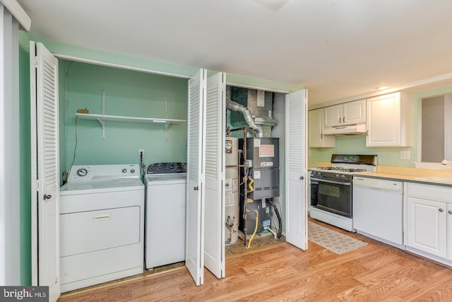 laundry area with light wood finished floors, washing machine and dryer, gas water heater, laundry area, and heating unit