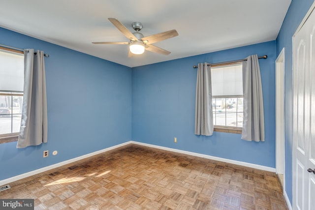 unfurnished room with visible vents, a ceiling fan, and baseboards