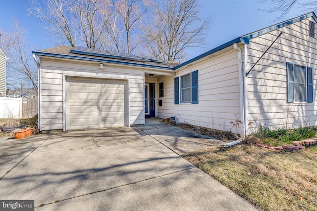 view of front of house with solar panels, an attached garage, fence, and driveway