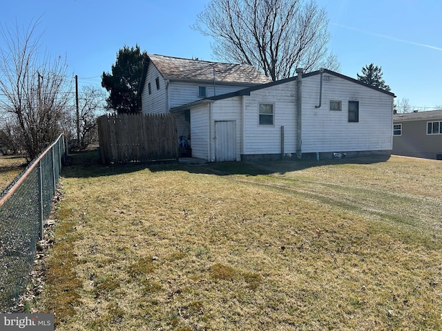 view of side of home with a lawn and fence