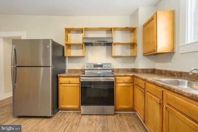 kitchen with a sink, light wood-style flooring, stainless steel appliances, wall chimney exhaust hood, and open shelves